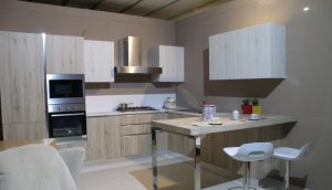 Diseño de cocina con aire industrial, muebles de cocina en madera clara, campana en acero y electrodomésticos a la vista