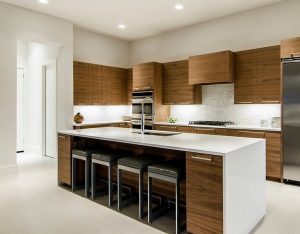 Diseño de cocina con isla XL, muebles de cocina en color madera oscuro y superficies en blanco, con detalles en gris