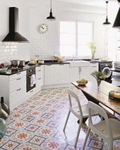 Diseño de cocina de color blanco y negro con los pisos en mosaico hidráulicos en tonos amarillos y azules, muebles de cocina en blanco con encimeras en negro