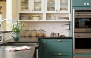 Diseño de cocina de color verde, con encimeras en negro, estilo clásico americano, muebles de cocina en verde y vitrinas en blanco